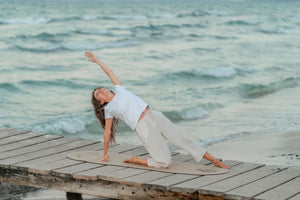 Somatisches Yoga: Jasmin steht in der Yogahaltung Baum auf der ovalen FLOWALOHA-Korkmatte
